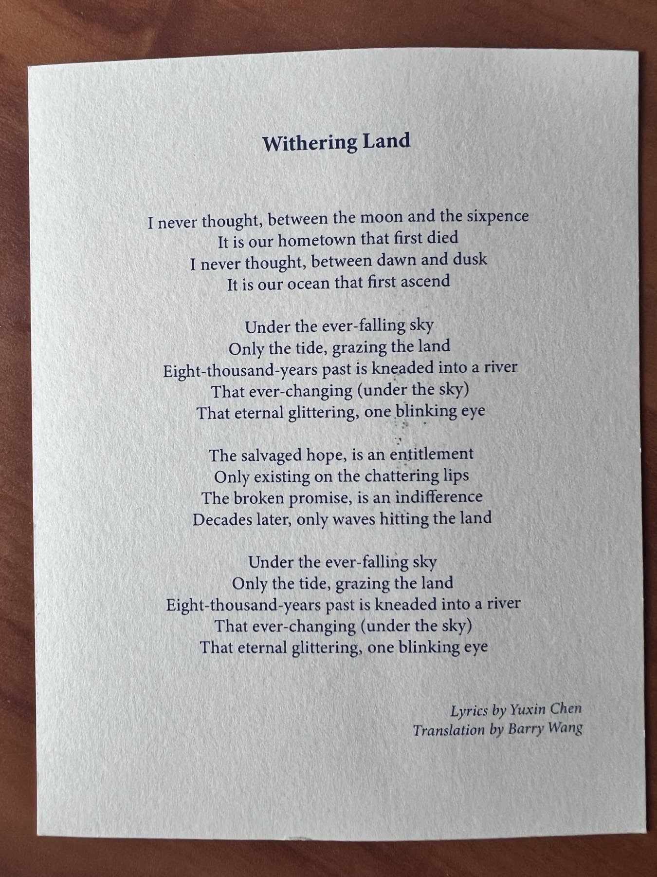 A printed lyric sheet for &ldquo;Withering Land&rdquo; on textured paper, with the English translation set below the title.