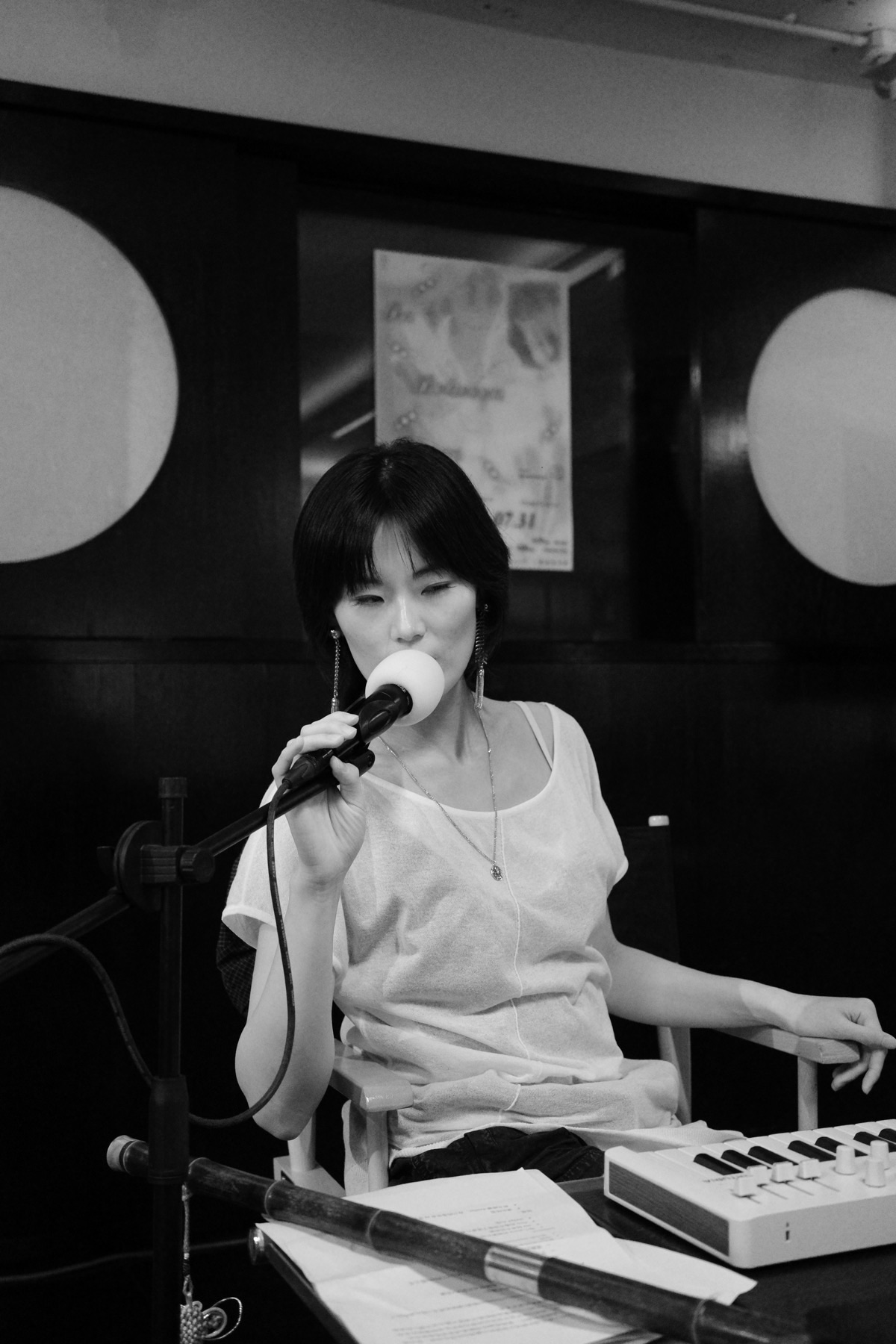 Morning Close singing into a microphone while playing a small keyboard at a live performance.